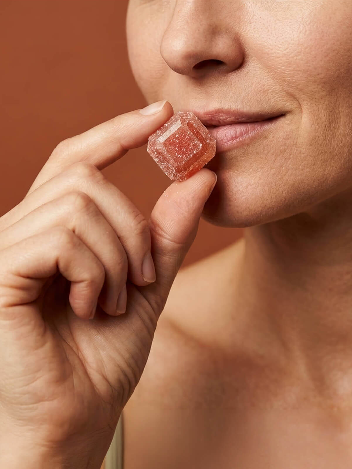 Woman holding a Crescent creatine gummy to her lips