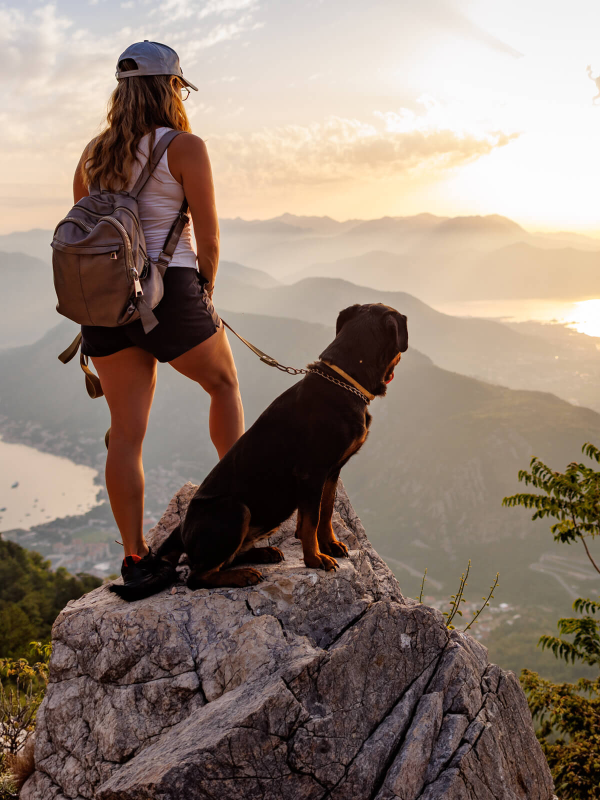 Woman hiking at sunset with her dog, overlooking mountains